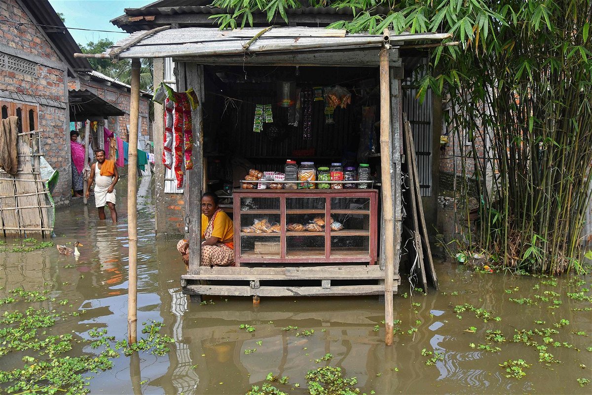 <i>Biju Boro/AFP/Getty Images</i><br/>A woman sits at her partially submerged shop in the flood affected area of Rangia