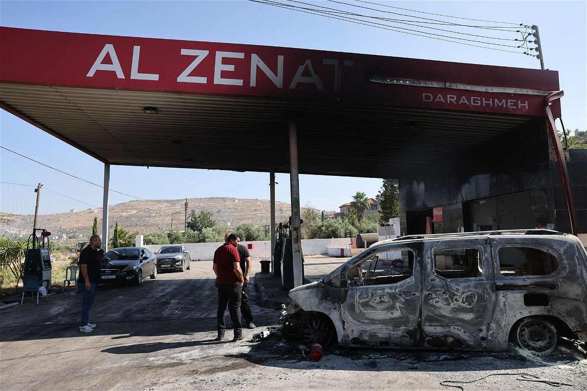 <i>Ahmad Gharabli/AFP/Getty Images</i><br/>People stand near a burnt car