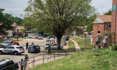 Residents watch as Baltimore Police investigate the site of a mass shooting in the Brooklyn Homes neighborhood on July 2.