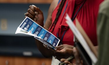 A woman holds a flyer at a career fair in Wilmington