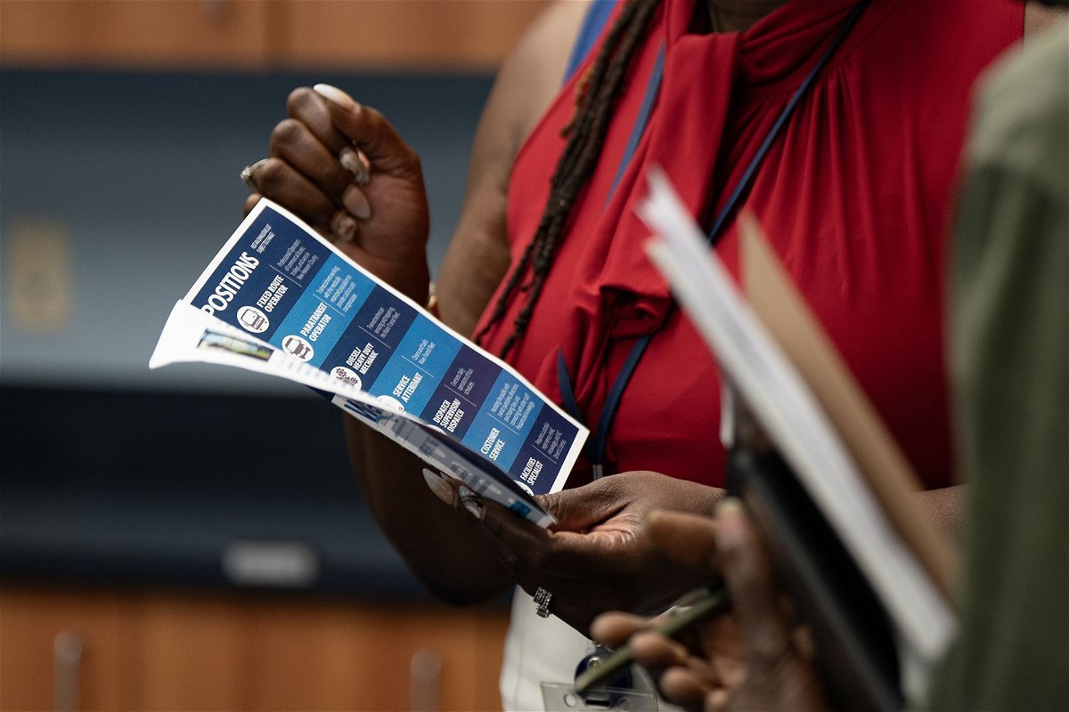 <i>Allison Joyce/Bloomberg/Getty Images</i><br/>A woman holds a flyer at a career fair in Wilmington