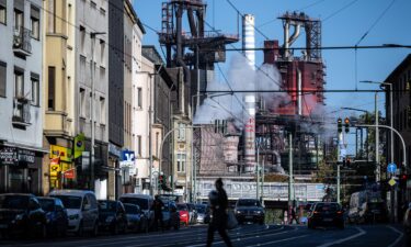 People cross a street as the ThyssenKrupp steel factory looms behind on October 6