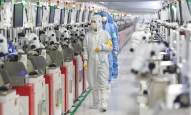 Employees operate machines at a dust-free workshop of a semiconductor factory on March 1 in Siyang County
