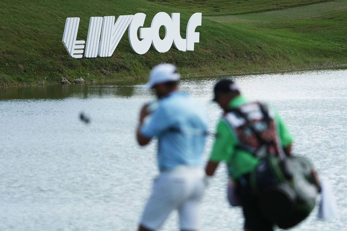 <i>Patrick Smith/LIV Golf/Getty Images</i><br/>A golfer and caddie walk by LIV Golf signage during the team championship stroke-play round of the LIV Golf Invitational - Miami at Trump National Doral Miami on October 30