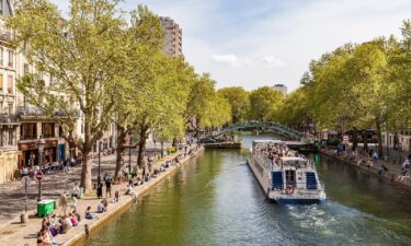 A sightseeing boat goes down Canal Saint Martin in Paris and you can get a discount for a place to stay here and other top-tier cities if you are willing to take a chance on very last-minute accommodations.