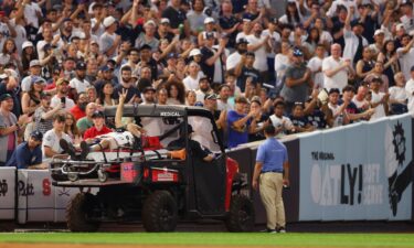 Pete Stendel waves to the crowd as he is carted off the field after getting hit by an errant throw in the fifth inning during the game between the New York Yankees and the Baltimore Orioles.