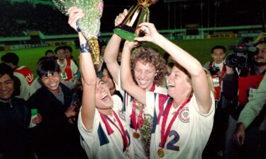 Michelle Akers (C) holds the Women's World Cup trophy with teammates Julie Foudy (L) and Carin Jennings (R).