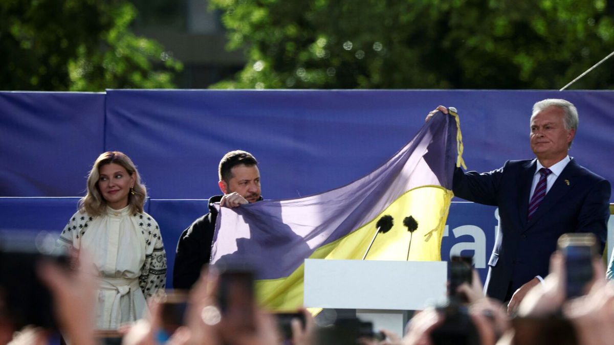 <i>Kacper Pempel/Reuters</i><br/>Ukrainian President Volodymyr Zelensky and Lithuanian President Gitanas Nauseda hold a Ukrainian flag from the front line of the war with Russia
