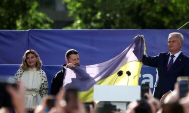 Ukrainian President Volodymyr Zelensky and Lithuanian President Gitanas Nauseda hold a Ukrainian flag from the front line of the war with Russia