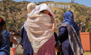 Tourists protect a sleeping child from the sun as they visit the Hollywood sign landmark in Los Angeles on July 12.