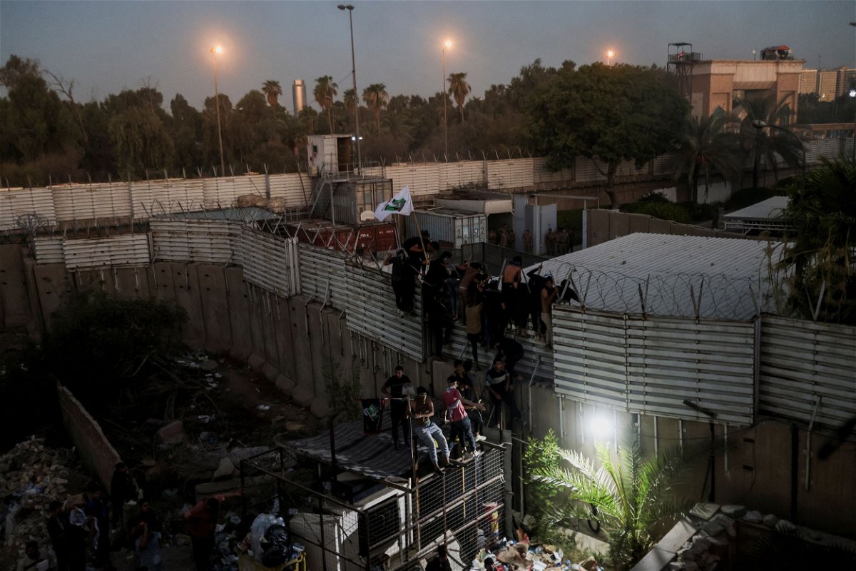 <i>Ahmed Saad/Reuters</i><br/>Protesters climb a fence near the Swedish embassy in Baghdad on July 20.