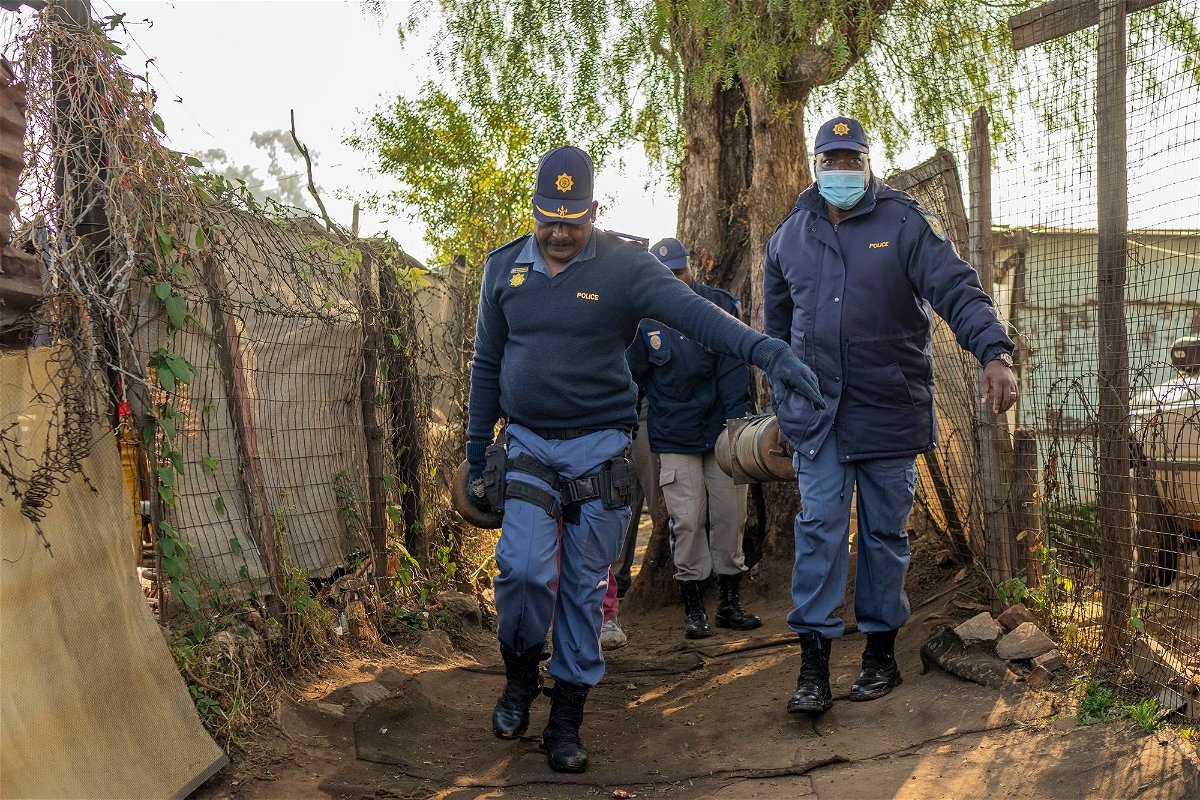 <i>Jerome Delay/AP</i><br/>South African police officers remove gas cylinders used by illegal gold miners in the Angelo Informal Settlement in Boksburg