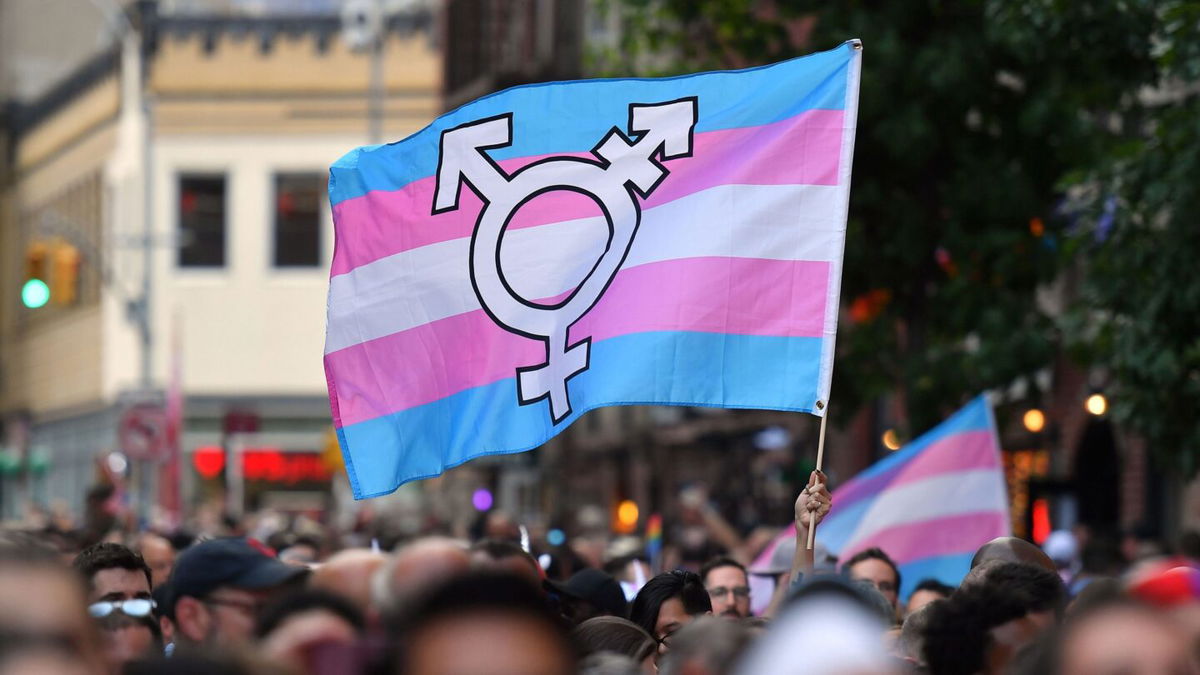 <i>Angela Weiss/AFP/Getty Images</i><br/>A person holds a transgender pride flag as people gather on Christopher Street outside the Stonewall Inn for a rally to mark the 50th anniversary of the Stonewall Riots in New York