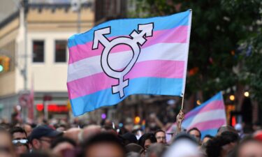 A person holds a transgender pride flag as people gather on Christopher Street outside the Stonewall Inn for a rally to mark the 50th anniversary of the Stonewall Riots in New York