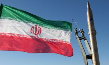 An Iranian flag flutters next to a ground-to-ground Sajil missile before being launched at an undisclosed location in Iran on November 12