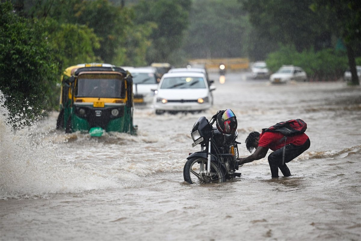 <i>Sanchit Khanna/Hindustan Times/Getty Images</i><br/>Commuters move through flooded streets after heavy rains in New Delhi on July 9