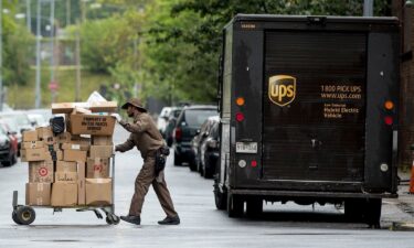 A delivery man pushes a cart full of packages to deliver to an apartment building.