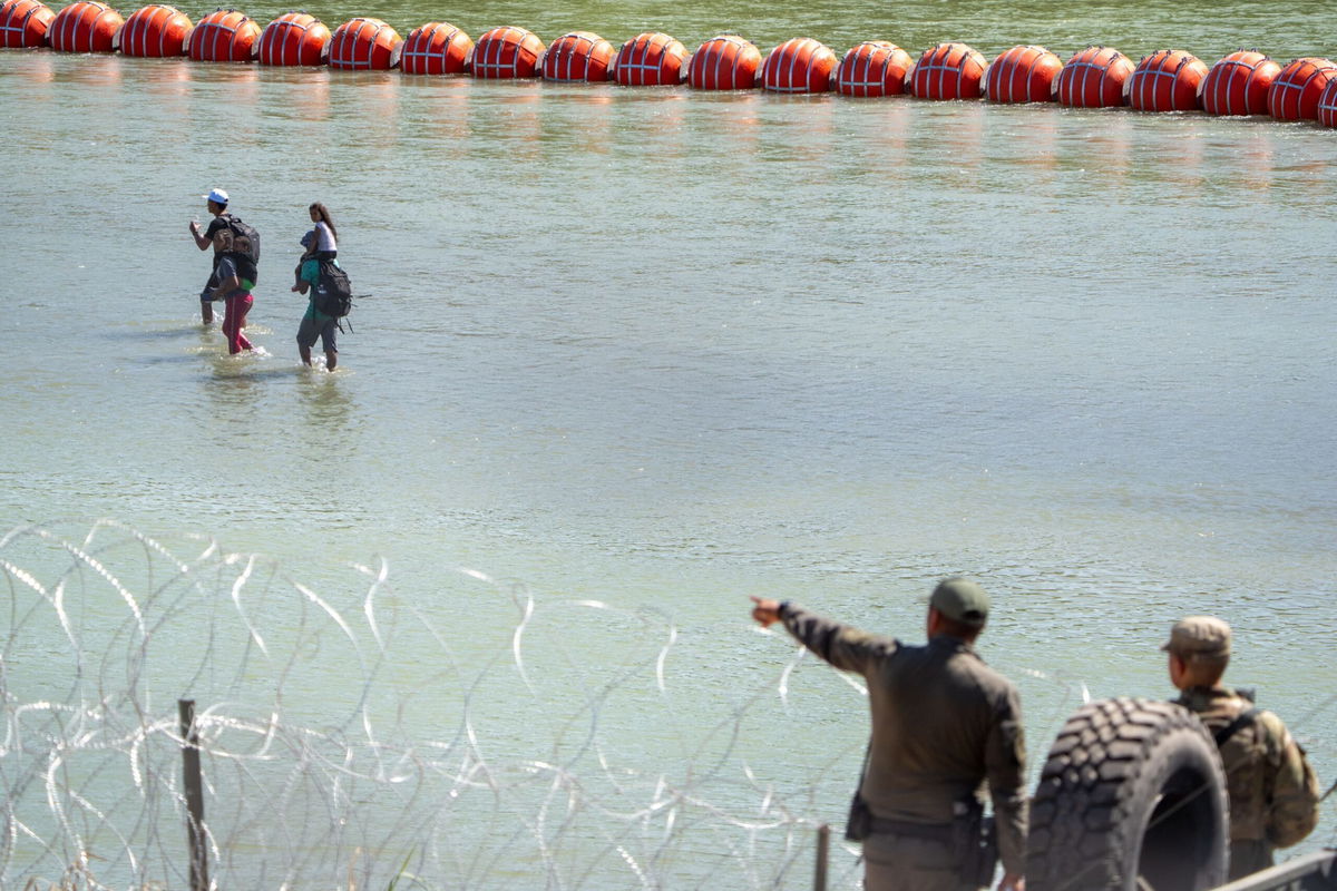 <i>Suzanne Cordeiro/AFP/Getty Images</i><br/>Texas Department of Public Safety (DPS) highway patrol troopers look over the Rio Grande as migrants walk by a string of buoys placed on the water along the Rio Grande border with Mexico in Eagle Pass