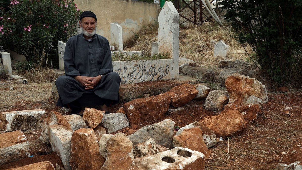<i>Omar Albam/AP</i><br/>Mohammed Hassan Masto sits next to the grave of his brother Lutfi