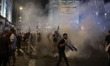 Israeli demonstrators hold flags and burn flares as they block the Ayalon highway.