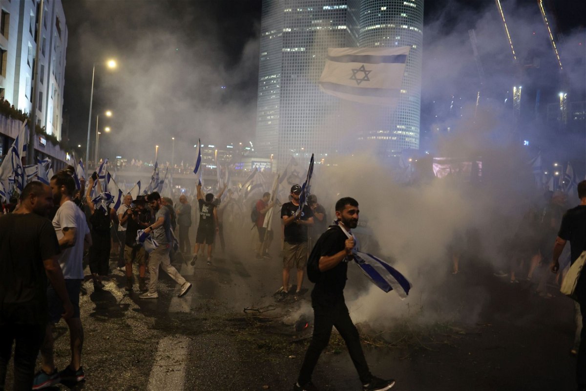 <i>Ilia Yefimovich/picture-alliance/dpa/AP</i><br/>Israeli demonstrators hold flags and burn flares as they block the Ayalon highway.