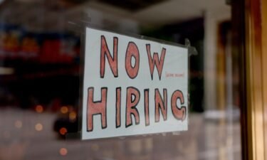 A 'Now Hiring' sign posted on the window of a business looking to hire workers on May 05