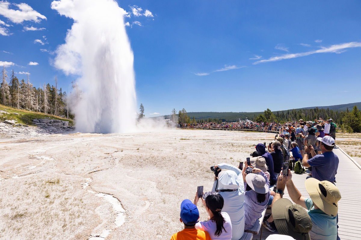 <i>Jacob W. Frank/NPS</i><br/>Throngs of visitors watch a Grand Geyser eruption at Yellowstone National Park on July 19.