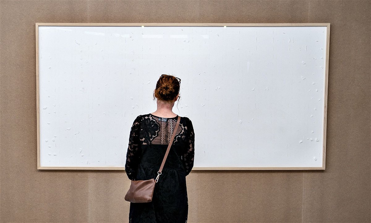 A woman stands in front of an empty frame hung up at the Kunsten Museum in Aalborg, Denmark. The Danish museum loaned an artist more than $76,000 worth of Danish krone in cash to recreate old artworks of his using the banknotes.