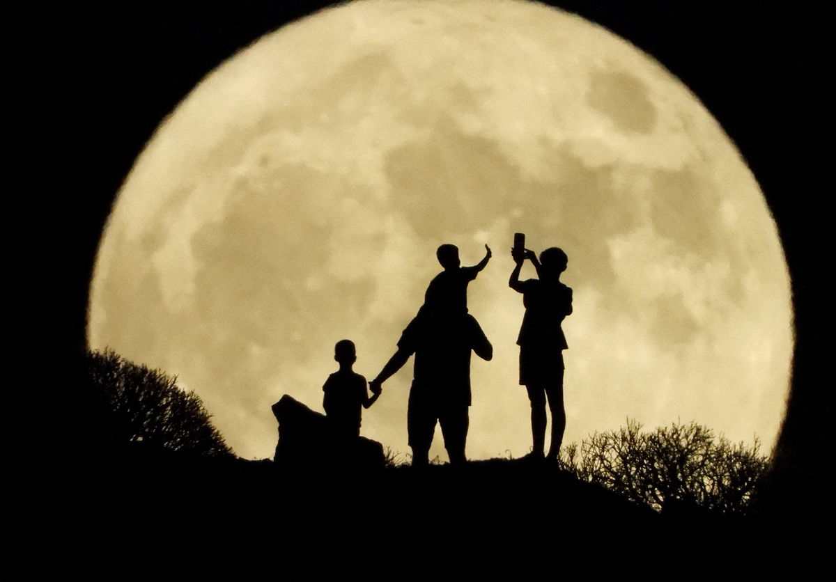 A family stand with the full moon known as the 