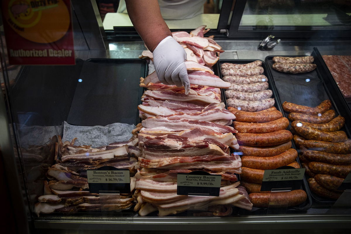 A worker adjusts cuts of bacon for sale at a butcher shop in the Union Market district in Washington, D.C., in August 2022.  As overall US inflation heated up last month, consumers got some relief at grocery stores.