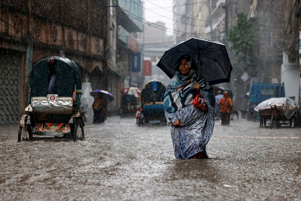 A woman holding an umbrella walks along a flooded street during heavy rain in Dhaka, Bangladesh in June.