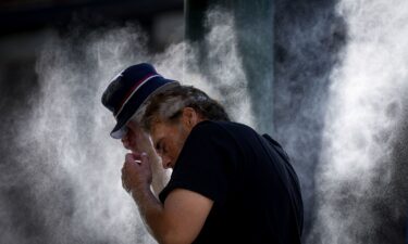 A man cools off at a temporary misting station deployed by the city in the Downtown Eastside due to a heat wave