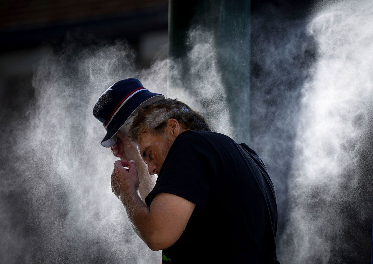 <i>Darryl Dyck/The Canadian Press/AP</i><br/>A man cools off at a temporary misting station deployed by the city in the Downtown Eastside due to a heat wave