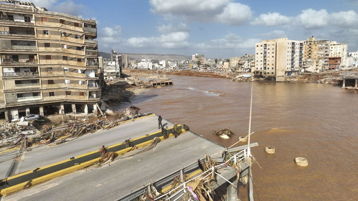 <i>AFP/Getty Images</i><br/>People walk past the body of a flash flood victim in the back of a pickup truck in Derna