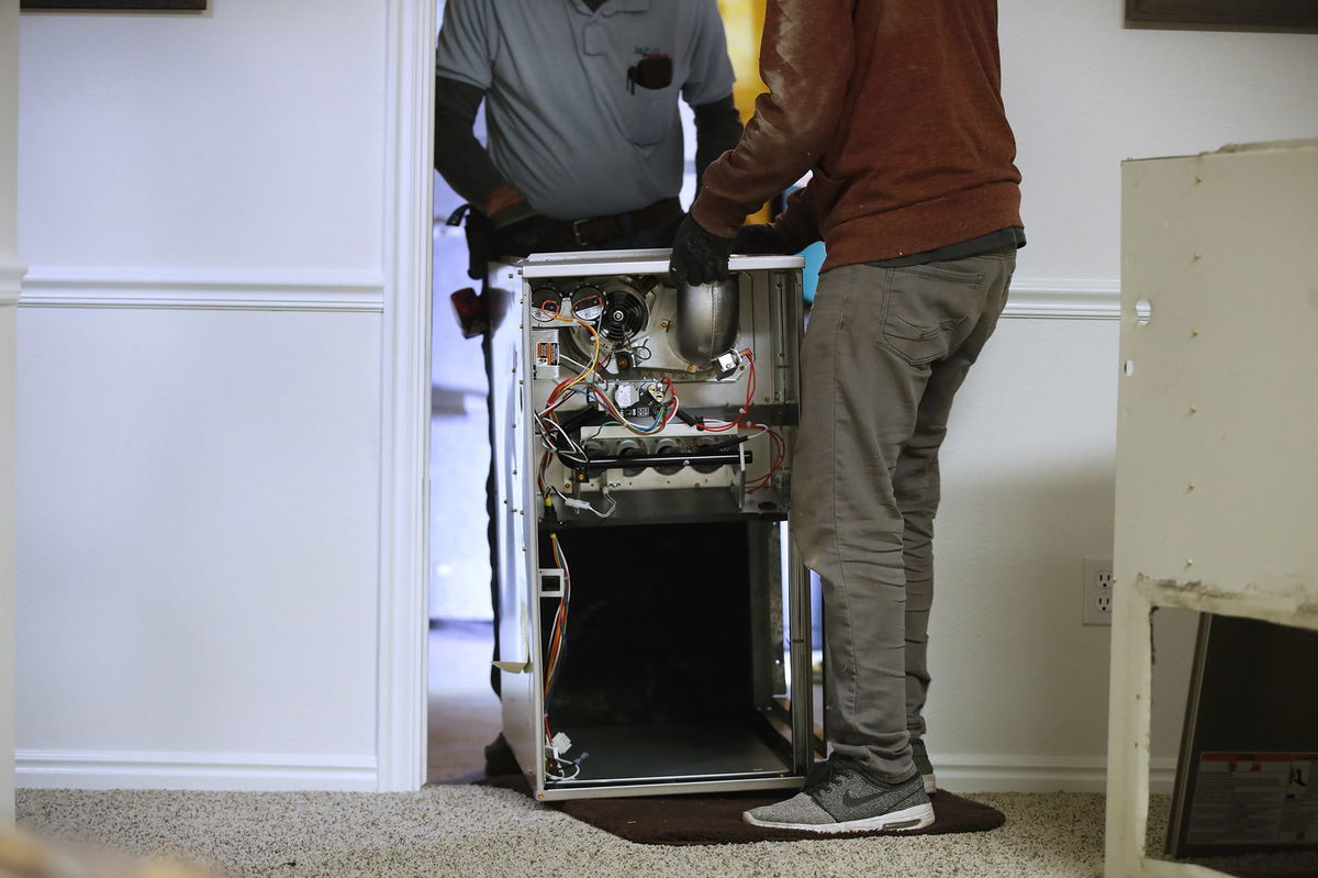 Workers carry a new Carrier natural gas furnace to install at a residential home in Spanish Fork, Utah, in October 2021. Natural gas heating, which is used by just under half of US homes, is expected to cost an average of $726 this winter.