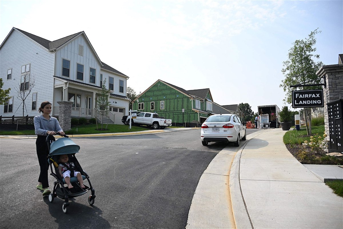 A person pushes a child in a stroller in a new housing development in Fairfax, Virginia, on August 22. US pending home sales ticked up in September despite mortgage rates surging over 7%.