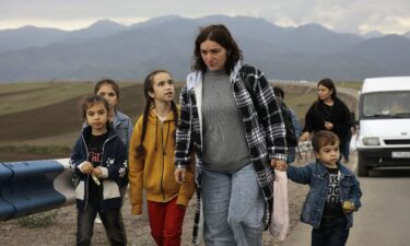 Refugees ride in the back of a truck as they arrive in Kornidzor