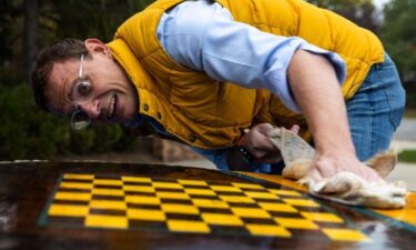 Tim Cayford prepares a stump for another coat of varnish on a tree stump at Dundee Elementary on October 25. Cayford put a chessboard on the stump.