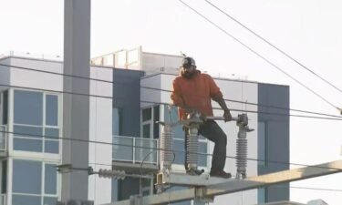 A man is seen atop a power pole apparatus above the Caltrain station platform at Fourth and King Streets in San Francisco in a hours-long standoff.
