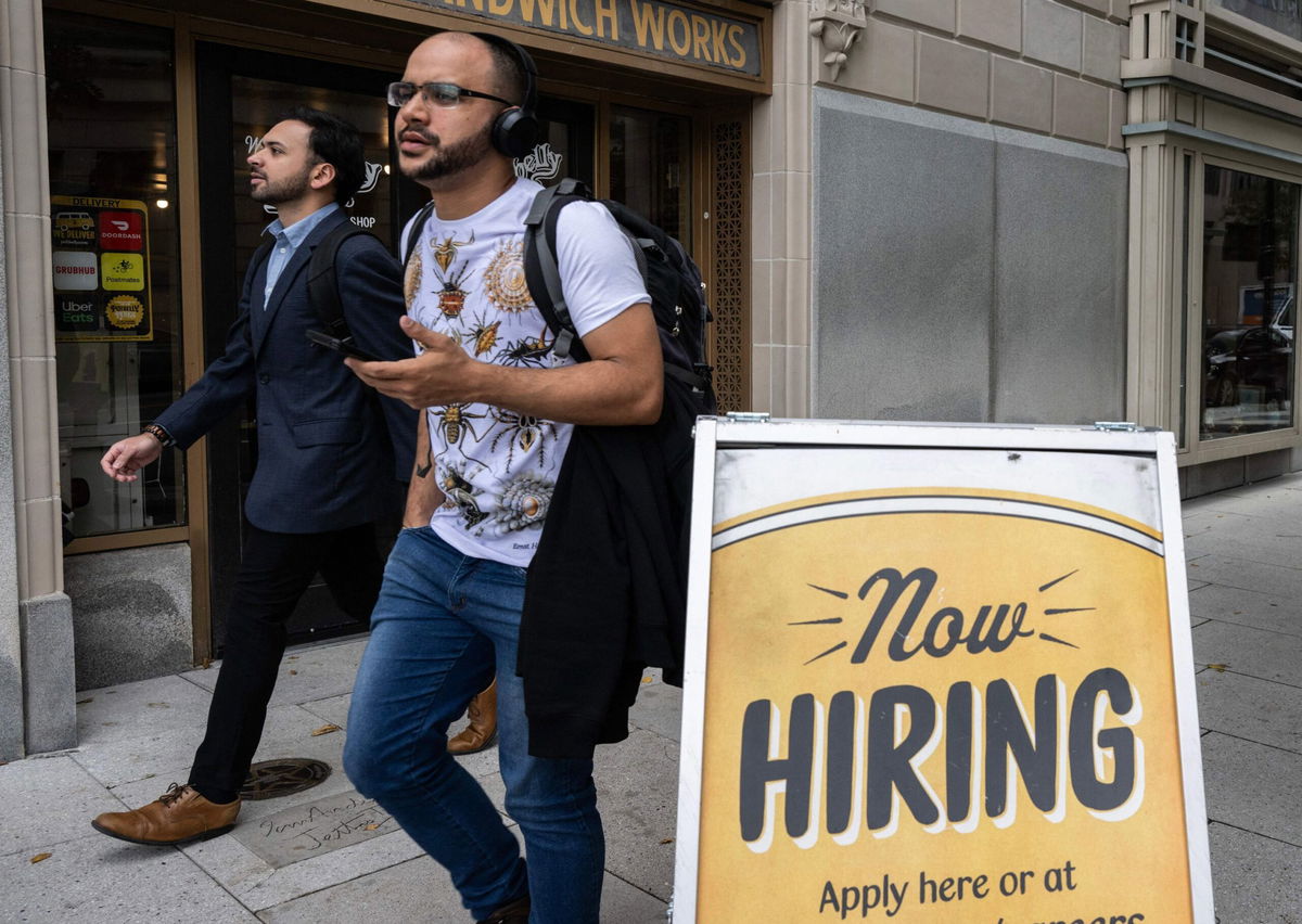 The US economy added 150,000 jobs last month. In this image people walk past a restaurant, with a hiring sign outside, in Washington, DC on October 5.