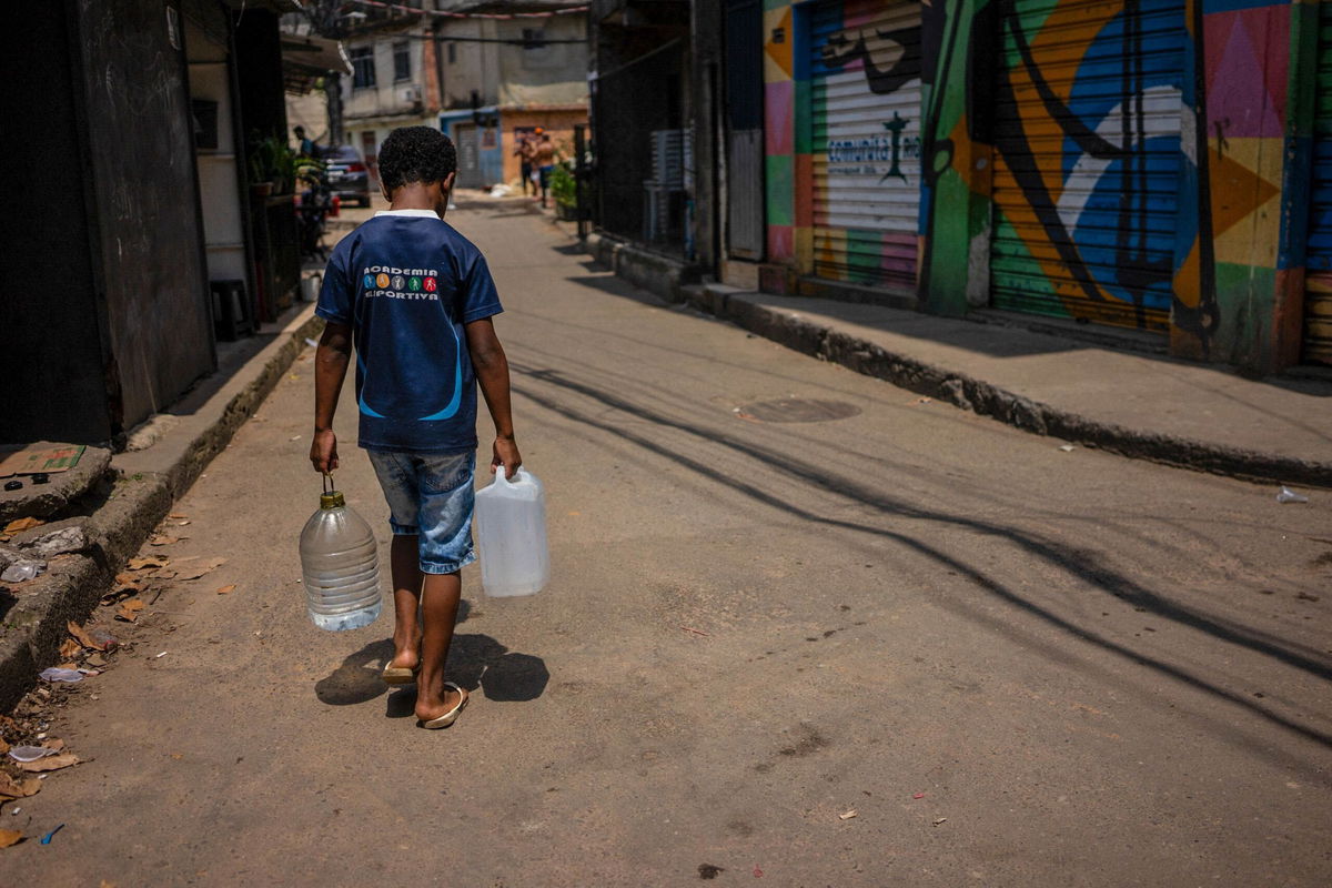 A resident of Rocinha carrying water collected from a natural spring during a heat wave in Rio de Janeiro, Brazil, on November 17.