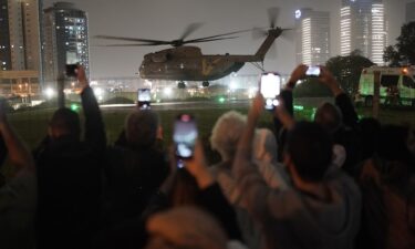 A group of Israelis watch as a helicopter carrying hostages released from Gaza lands at the helipad of the Schneider Children's Medical Center in Petah Tikva