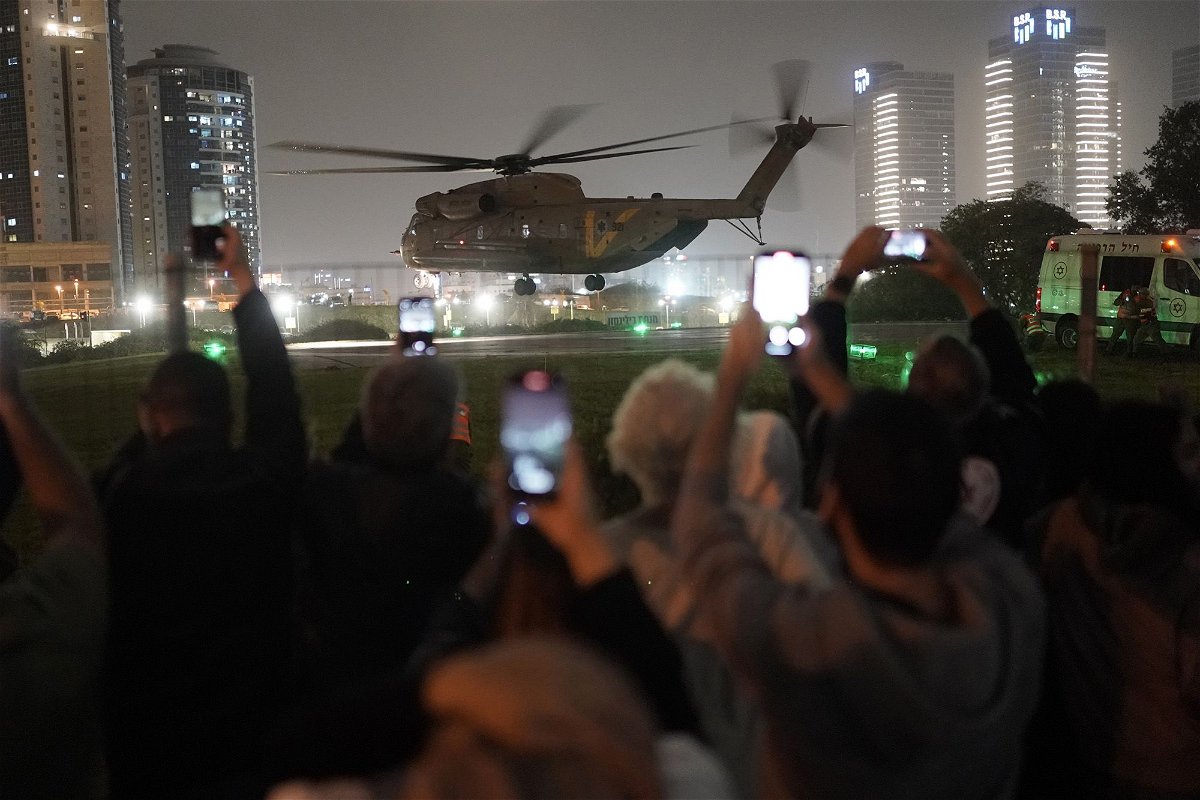 <i>Leo Correa/AP</i><br/>A group of Israelis watch as a helicopter carrying hostages released from Gaza lands at the helipad of the Schneider Children's Medical Center in Petah Tikva