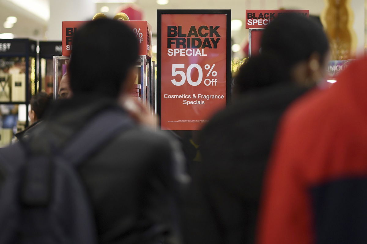 People walk past advertised Black Friday discount signs at the Macy's retail store inside the Queens Center Mall, New York, NY, November 24.