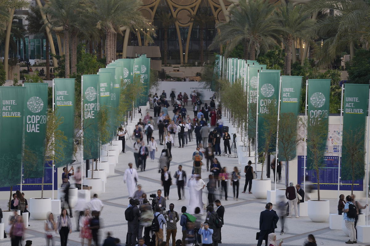 <i>Peter Dejong/AP</i><br/>People walk through the COP28 U.N. Climate Summit