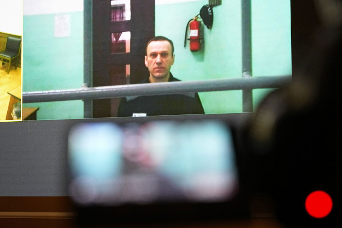 <i>Alexander Zemlianichenko/AP</i><br/>Alexei Navalny is seen on a TV screen as he appears by video link at a court hearing in Moscow on June 22