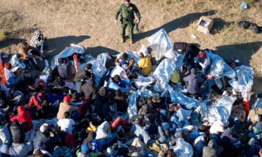 A US Border Patrol agent speaks with immigrants waiting to be processed after crossing from Mexico into the United States on December 17