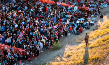 A US Border Patrol agent watches over migrants waiting to be processed after crossing from Mexico into the United States on December 17 in Eagle Pass