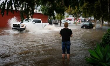 A man watches motorists drive through a flooded street during a rain storm Thursday in Santa Barbara