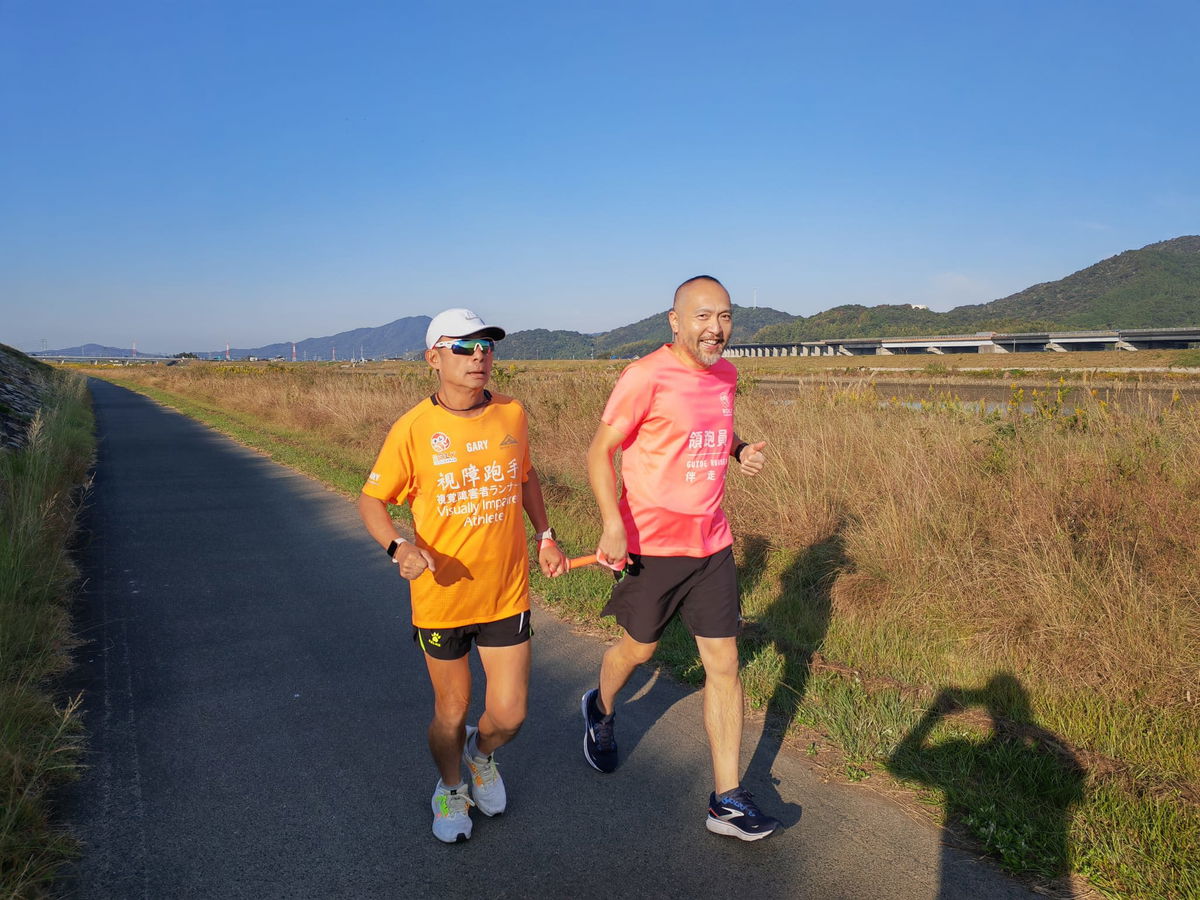 Leung jogs alongside a guide during his recent long-distance run in Japan.